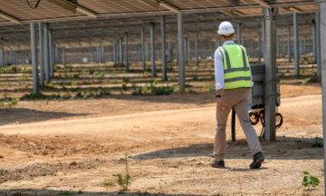 a-man-in-a-hard-hat-and-safety-vest-standing-in-a-greenhouse.jpg A man in a hard hat and safety vest standing in a greenhouse